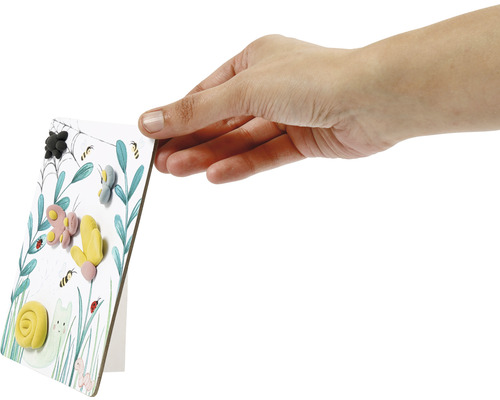 Eine Hand hält eine Karte mit Motiven aus Knete.