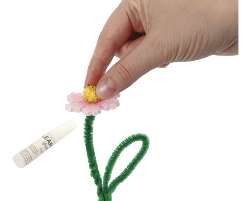 Bastelanleitung: Hand befestigt ein Element auf einer Blume mit Pfeifenputzerstiel und Klebstoff