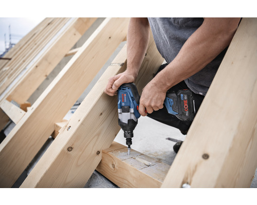 Handwerker schraubt mit einem Akku-Schlagschrauber Schrauben in eine Holzkonstruktion.