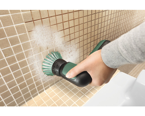 Eine Person reinigt Fliesen mit einer elektrischen Bürste.