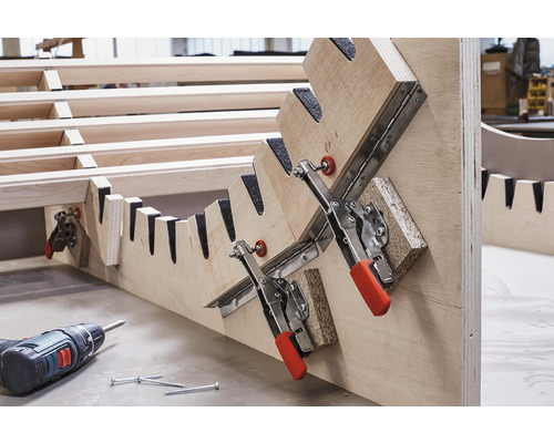 Holzkonstruktion mit Spannvorrichtung, Akkuschrauber und Schrauben.