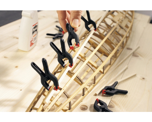 Modellbau eines Bootsrumpfs mit Federzwingen auf einer Holzoberfläche