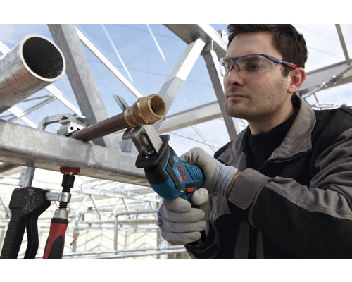 Ein Mann sägt ein Rohr mit einer Bosch Säbelsäge, während er eine Schutzbrille und Handschuhe trägt.