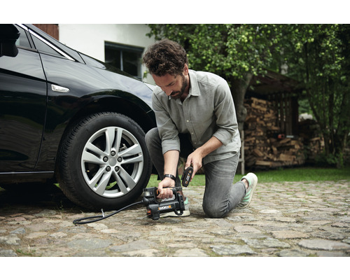 Mann befüllt Autoreifen mit einem tragbaren Kompressor.