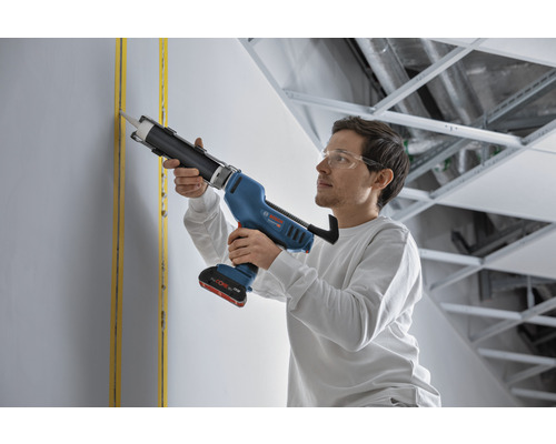 Ein Mann verwendet eine Akku-Kartuschenpistole von Bosch zum Verfugen einer Wand.