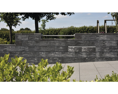 Eine Mauer aus Betonsteinen in einem Garten