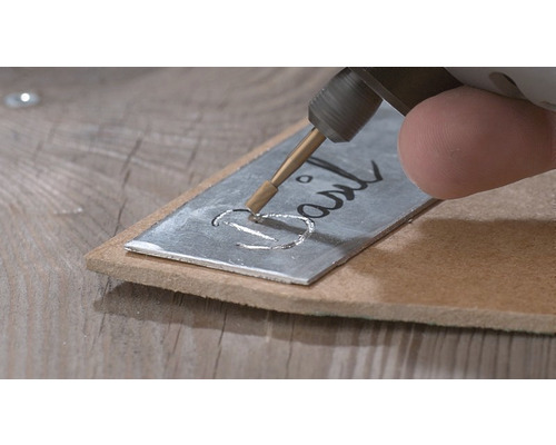Gravierwerkzeug beim Beschriften eines Metallschildes mit dem Wort ''Basil''
