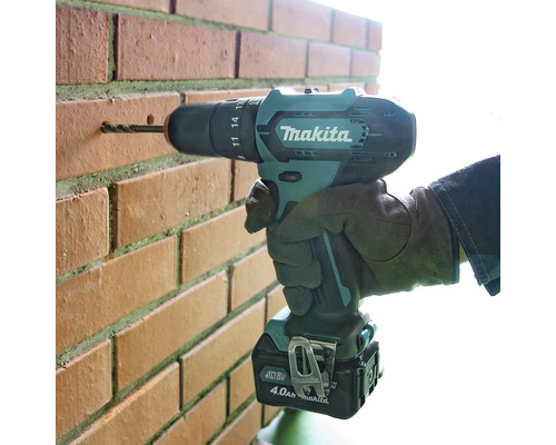 Makita Logo. Akku-Bohrschrauber bohrt in eine Ziegelwand.
