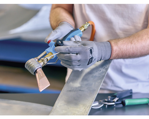 Person benutzt eine Lötlampe für Blecharbeiten.