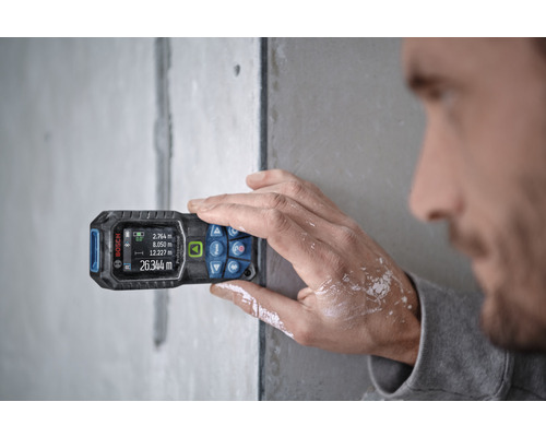 Mann misst Wand mit Laser-Entfernungsmesser von Bosch