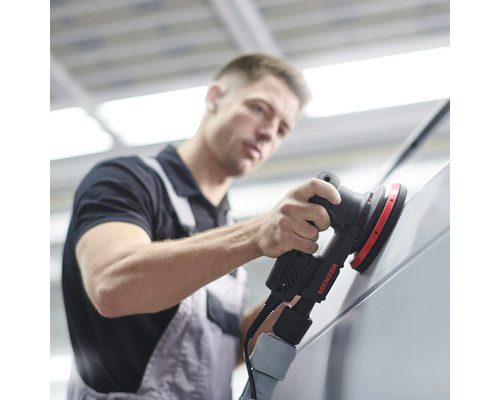 Ein Mann verwendet einen Exzenterschleifer von Menzer zum Schleifen einer Oberfläche.