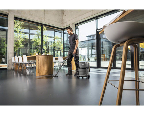Ein Mann reinigt mit einem Nass-Trockensauger einen Boden in einem Büro.