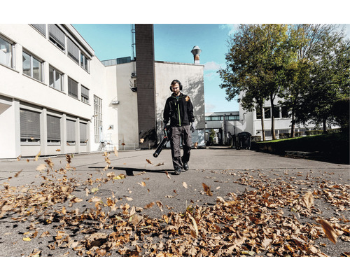 Mann mit Laubbläser im Außeneinsatz zur Reinigung von Blättern.