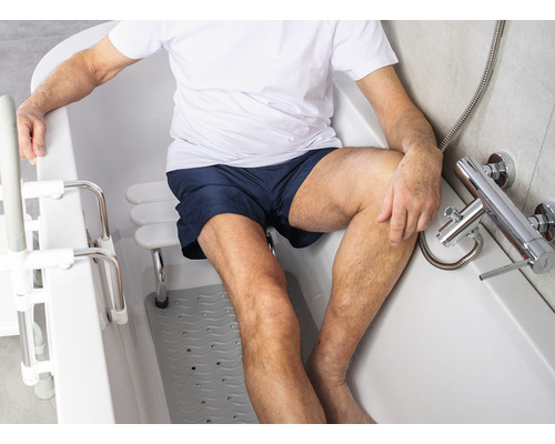 Mann sitzt in einer Badewanne mit Einstiegshilfe und Wannensitz