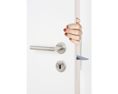 Eine Hand hält eine Tür mit Türklinke und Türkeil offen.