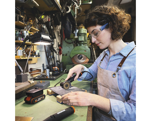 Frau arbeitet mit einem Trennschleifer in einer Werkstatt.