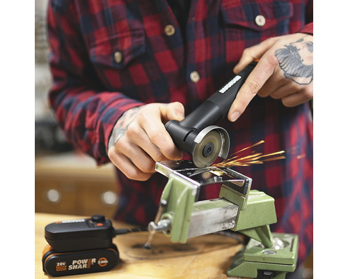 Eine Person benutzt einen Akku-Winkelschleifer mit einer Metallklemme und einer Batterie