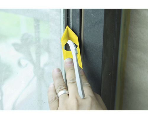 Hand drückt Dichtungsband mit Fugenglätter in Fensterrahmen