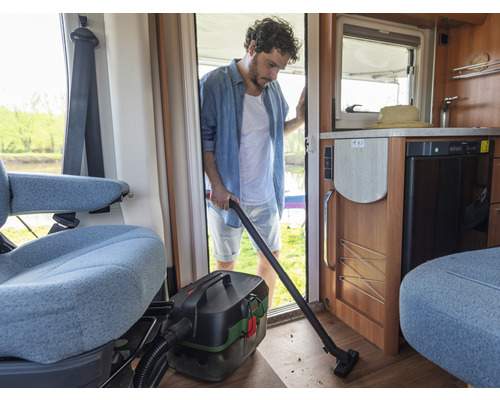 Ein Mann saugt das Innere eines Wohnmobils mit einem Mehrzwecksauger.