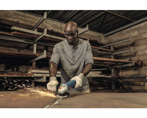 Ein Mann schleift mit einer Flex Metall, wobei Funken sprühen.