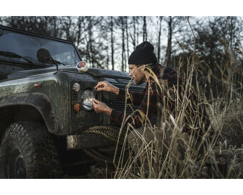 Mann bringt Steinschlagschutzfolie auf Scheinwerfer an