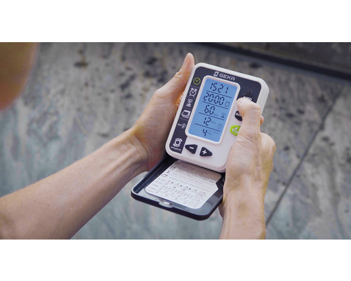 Eine Person hält eine Geka Bewässerungssteuerung in den Händen und bedient sie.