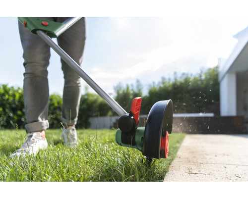 Rasentrimmer im Einsatz zum Kantenschneiden eines Rasens