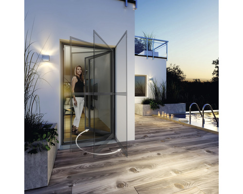 Drehflügeltür mit Insektenschutz in geöffneter Position vor einer Hausfassade