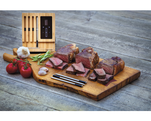 Drei Steaks mit Tomaten, Knoblauch, Rosmarin, Garthermometer und Holzbrett