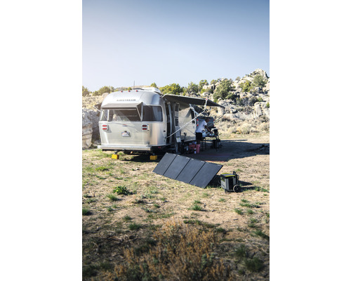 Silberner Wohnwagen mit Solaranlage in der Natur