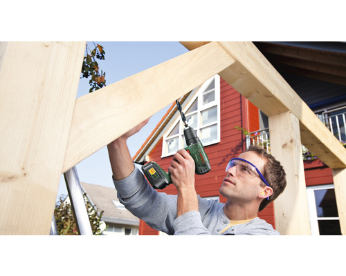 Ein Mann bohrt mit einem Akkubohrer ein Holzstück.