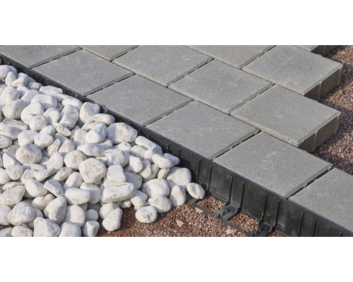Graue Pflastersteine neben weißen Zierkieseln und einer schwarzen Rasenkante