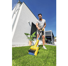Mann benutzt eine Fugenbürste im Garten