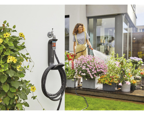 Gartenszene mit Wand-Schlauchbox und Frau, die Blumen gießt