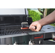 Person reinigt Grillrost mit Grillbürste