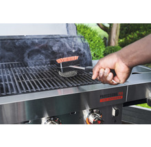 Eine Person reinigt einen Grill mit einer Grillbürste.