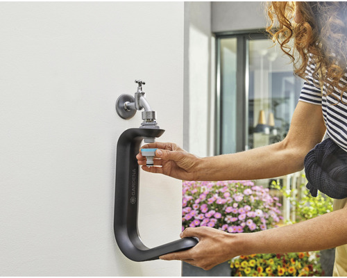 Gardena Wasserhahn-Anschluss mit Person beim Anschließen eines Schlauchstücks an einen Wasserhahn