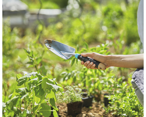 Eine Person hält eine Gardena Pflanzschaufel im Garten.