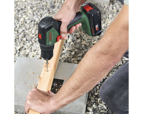 Eine Person schraubt mit einem Akku-Bohrschrauber eine Schraube in ein Holzbrett