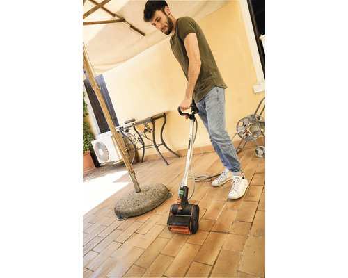 Mann benutzt einen elektrischen Terrassenreiniger auf einer gefliesten Terrasse.