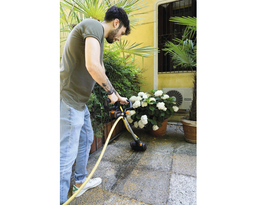 Mann reinigt Terrasse mit Terrassenreiniger.