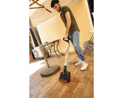 Mann reinigt eine Terrasse mit einem elektrischen Terrassenreiniger.