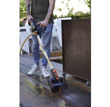 Eine Person benutzt einen Terrassenreiniger zum Reinigen einer Holzterrasse.
