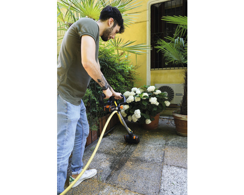 Mann reinigt Terrasse mit einem Terrassenreiniger.