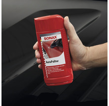 Sonax Autopolitur Flasche wird von einer Hand gehalten
