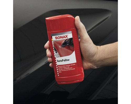 Sonax Autopolitur Flasche wird von einer Hand gehalten