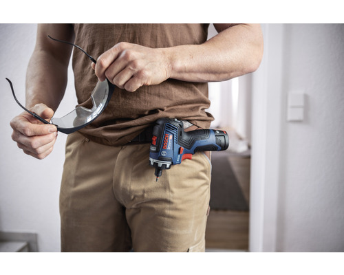 Mann mit Schutzbrille und Akku-Bohrschrauber am Gürtel