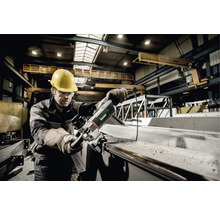 Ein Mann mit Schutzhelm und Schutzbrille bedient eine Metabo Blechnagermaschine in einer Werkshalle.