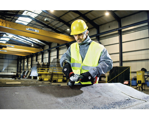 Ein Arbeiter schleift Metall mit einem Winkelschleifer in einer Fabrik.