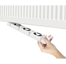 Eine Hand befestigt einen Heizkörperlüfter an einem Heizkörper.